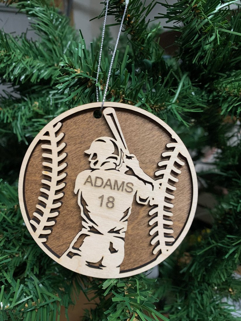 Personalized baseball ornament engraved with player name Adams and number 18, hanging on a Christmas tree