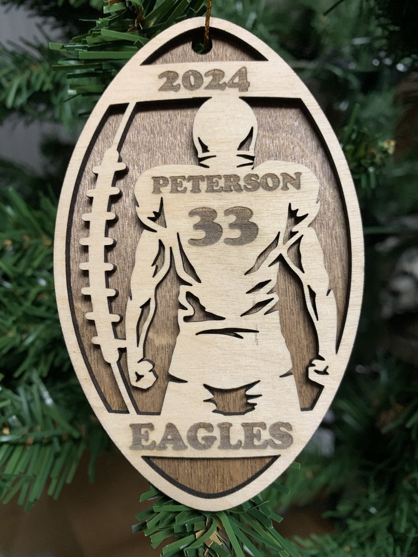 Personalized football ornament engraved with player name Peterson, number 33, team name Eagles, and the year 2024