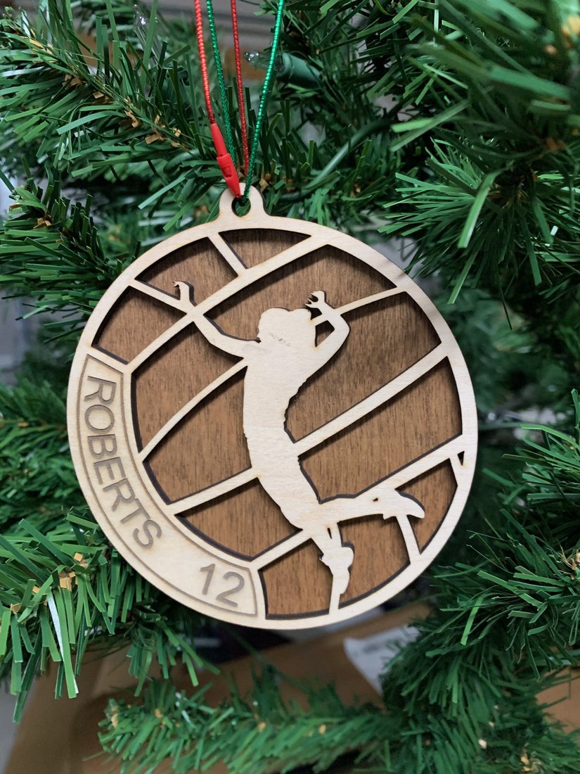 Personalized volleyball ornament engraved with player name Roberts and number 12, hanging on a Christmas tree